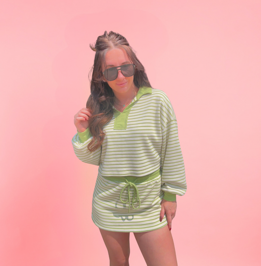 Woman wearing a green and white striped outfit against a pink background